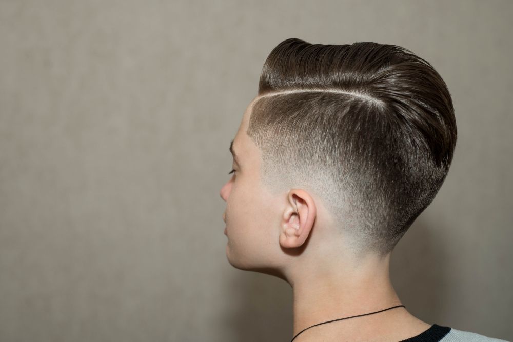 jeune garçon avec une coupe tendance : une raie à gauche en dégradé structuré